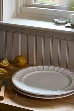 a white plate sitting on top of a wooden counter next to a knife and lemon