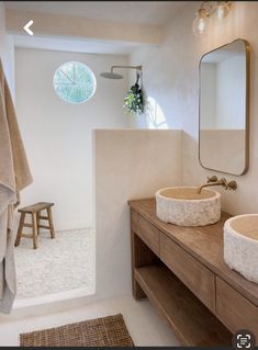 two sinks in a bathroom under a mirror and towel rack next to a wooden stool