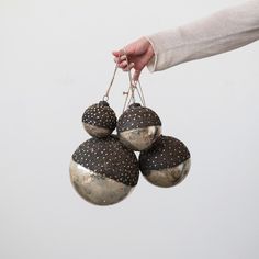 a person is holding four ornaments in their left hand and the other one has three balls hanging from it