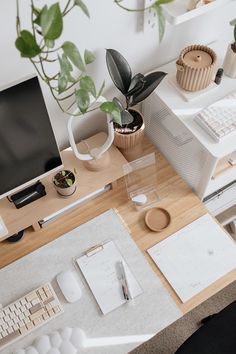 a desk with a computer, keyboard and plant on it next to other office supplies