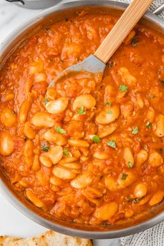 a pot filled with beans and sauce next to bread