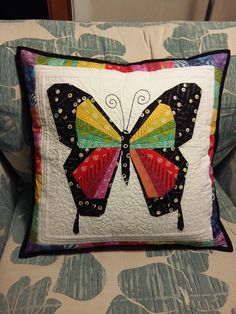 a colorful butterfly pillow sitting on top of a couch