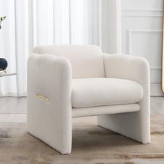 a white chair sitting on top of a hard wood floor next to a vase filled with flowers