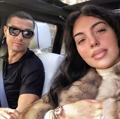 a man and woman sitting in the back seat of a car with fur on them