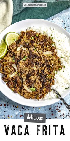 a white plate topped with meat and rice next to a lime wedge on the side