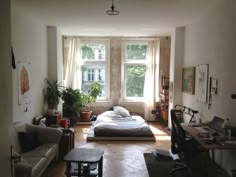 a bedroom with a bed, couch and desk in it's center area next to a window