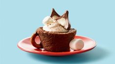 a chocolate cupcake with whipped cream and marshmallows on a red plate