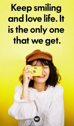 a woman taking a photo with her cell phone in front of a yellow background that says keep smiling and love life it is the only one that we get