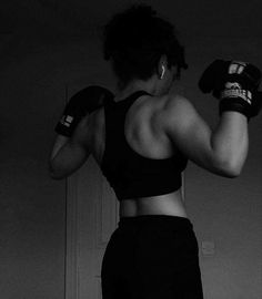 a woman wearing boxing gloves in a black and white photo with her back to the camera