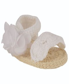 a pair of white crocheted shoes with a flower on the top and bottom