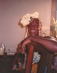 a woman sitting in a chair wearing a flower crown on her head and smiling at the camera