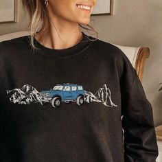 a woman wearing a black sweatshirt with a blue car on it