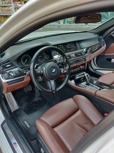 the interior of a car with brown leather seats and steering wheel controls on display in a showroom