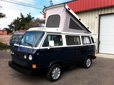 a van parked in front of a building with a camper attached to the roof