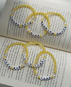 three bracelets made out of beads with words on them sitting on top of an open book