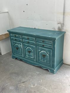 an old dresser is painted blue and sits in the middle of a room with white walls