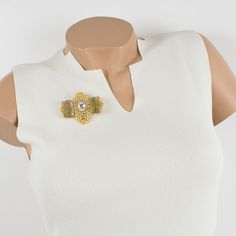 This lovely Gianfranco Ferre couture pin brooch features a dimensional gilt metal geometric shape, all paved with crystal clear rhinestones and topped with two massive champagne resin cabochons. A security closing clasp at the back with the Ferre, Made in Italy hallmark underside. Measurements: 2.50 in wide (6.3 cm) x 2.07 in high (5.2 cm).  Please see the measurements noted above in the description for the best approximate dimensions. Chic Gold Brooch For Evening, Chic Evening Jewelry Brooch, Chic Evening Brooch Jewelry, Designer Gold Brooches For Party, Luxury Gold-tone Brooch Jewelry, Luxury Gold-tone Jewelry Brooch, Chic Brooch Jewelry For Parties, Chic Gold Brooches For Party, Chic Party Brooch Jewelry