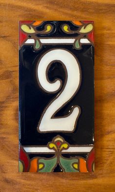 a black and white number two on a wooden table with an orange, green, yellow, and red design