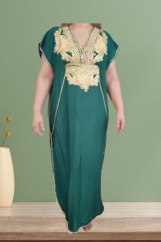 The Green Moroccan dress, often referred to "Kaftan", features intricate golden embroidery. It showcases a loose silhouette that provide elegance and comfort. The rich green color symbolizes nature and vitality, making it popular choice for various occasions, from weddings to festive gatherings. Festive Green Dabka Kaftan, Green Tunic Kaftan For Festive Occasions, Green V-neck Kaftan For Festive Occasions, Green Dabka Kaftan For Eid, Traditional Green Kaftan For Festive Occasions, Traditional Green V-neck Dress, Gold Embroidered Dress For Eid, Traditional Gold Maxi Dress For Eid, Traditional Green Dabka Kaftan