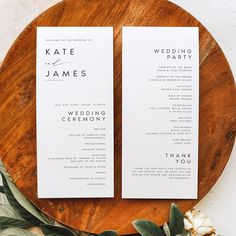 two white wedding programs sitting on top of a wooden plate