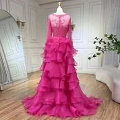 a dress on display in a room with white walls and wood flooring, including a mannequin wearing a pink gown