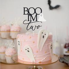 a pink cake with ghost decorations on it and a boo i'm taco sign