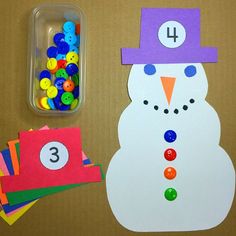 a snowman made out of paper and buttons next to a container of button holes