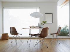 a dining room table with three chairs and a vase on the table next to it