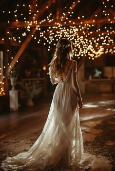 a woman in a white dress is standing outside at night with lights on the ceiling