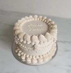 there is a white cake that has been decorated with shells and words on the side