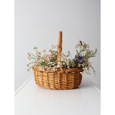 a wicker basket with flowers in it sitting on a white countertop next to a wall