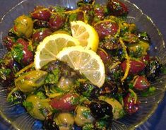 a glass bowl filled with olives and lemon slices