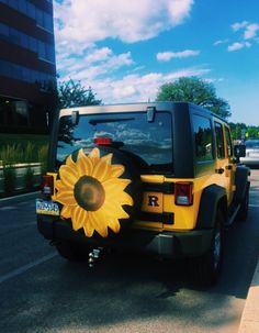 a yellow jeep with a large sunflower painted on it's tailgates