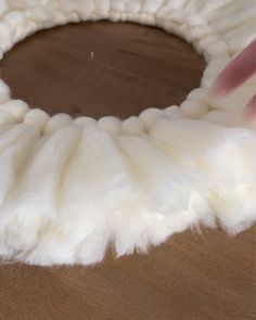 someone is making a wreath out of fake fur on a table with a wooden surface