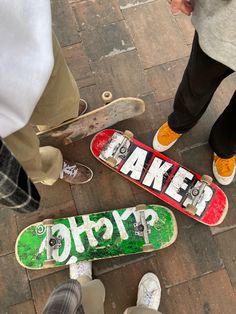 three skateboarders are standing on the ground with their boards in front of them