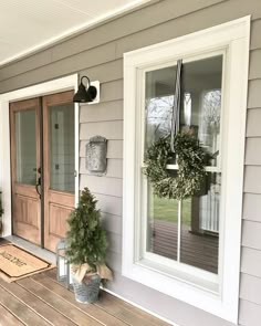 the front porch is decorated with wreaths and potted plants