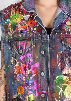 a woman wearing a jean jacket with colorful patches and buttons on the back of it