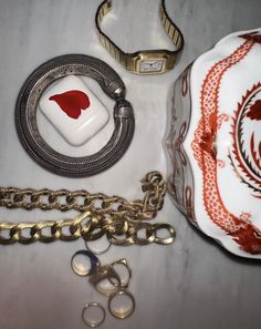 various items are laid out on a white tablecloth with gold chains and rings around them