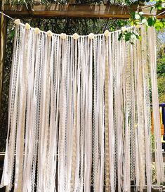 an outdoor wedding ceremony with white sheer curtains and pom poms hanging from the ceiling