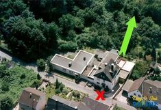 an aerial view of a house with a green arrow pointing to the roof and trees surrounding it