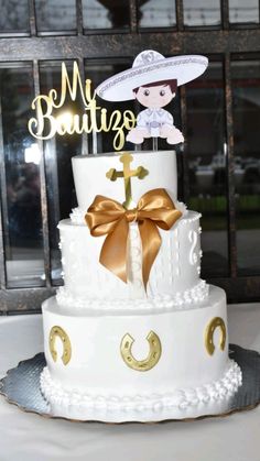 a three tiered cake decorated with gold ribbon and an acrylic topper