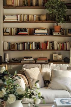 a living room filled with furniture and lots of books on the shelves above it's head