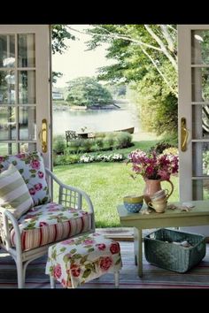 an open patio door with flowers on the table and two chairs in front of it