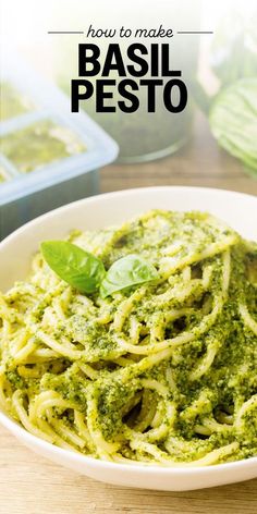 a white bowl filled with pesto pasta on top of a wooden table next to basil leaves