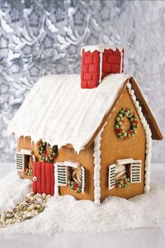 a gingerbread house with wreaths on the roof and shutters in the snow