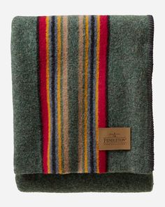 a blanket with multicolored stripes on the front and back, folded in green