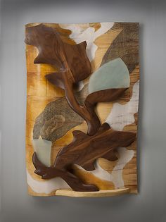 a piece of art made out of wood with leaves and rocks on the bottom side