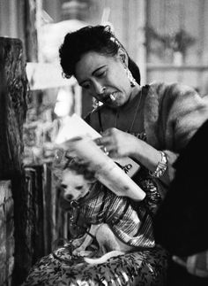 a black and white photo of a woman sitting on the floor with a dog in her lap