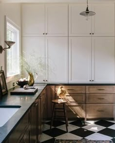 a kitchen with black and white checkered flooring, cabinets and stools in it