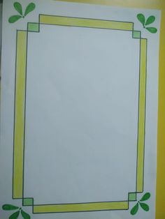 a white paper with green leaves and a yellow border around it on top of a table